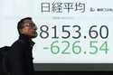 A person walks in front of an electronic stock board showing part of Japan's Nikkei index at a secu…